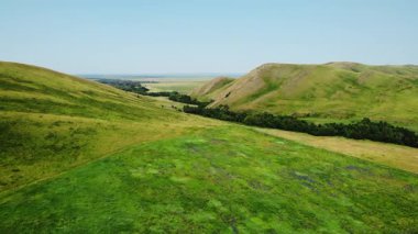 Sersemletici hava görüntüleri bulutsuz bir gökyüzünün altında yuvarlanan tepeler arasında güzel yeşil bir vadi üzerinde uçuyor.