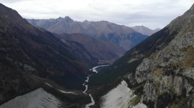 Bulutlu bir günde derin bir dağ geçidinde akan dolambaçlı bir nehrin görkemli hava perspektifi. Medya