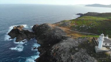 Kıyı şeridindeki Punta Robaleira 'daki beyaz deniz fenerinden uzaklaşan hava görüntüleri. Medya