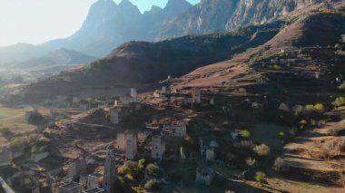 Ortaçağ köyünün üzerinde uçan hava manzarası engin bir dağ manzarasındaki taş kulelerle harabe. Medya