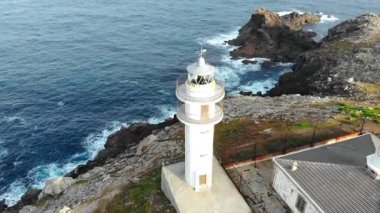 Atlantik Okyanusu 'nun yanındaki kayalık yamaçtaki beyaz bir deniz fenerinin insansız hava aracı görüntüleri. Medya