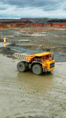 Çamurlu yoldan geçen iki sarı damperli kamyon, yüksek çözünürlüklü tekerlekler havuzda sıçrıyor, geniş.