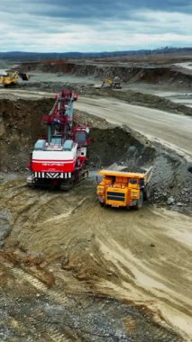 panoramic pit landscape with shovel and yellow haul truck, wide haul roads, layered benches and distant