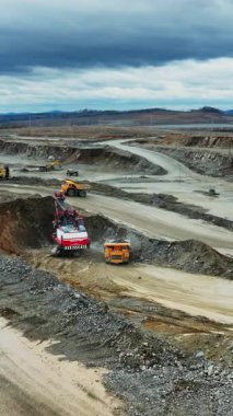 sweeping quarry haulroad heavy truck and excavator moving along winding route, aerial perspective shows graded