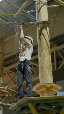 Güvenli kabloyu güvenli bir şekilde tırmanan dağcı, kapalı bir spor salonunda yüksek bir platforma tırmanarak odak ve hassasiyet gösteriyor. Yaratıcı