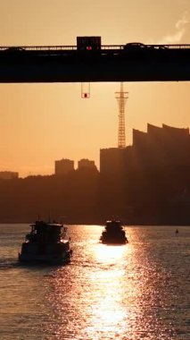 Gün batımında köprünün altında nehri geçen yolcu feribotu. Kırp