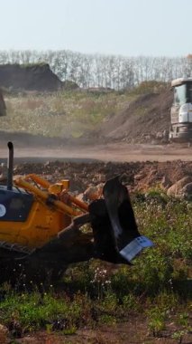 Sırbistan 'ın Vrsac kenti - Haziran 2025: İnşaat sahasında çalışan buldozer, toprak ve molozları hareket ettirirken, çöp kamyonları da malzeme taşıyor. Kırp