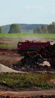 İnşaat makineleri büyük bir inşaat sahasında çakıl ve toprak taşıyor. Kırp