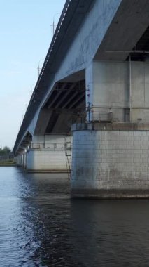 Uzak bir ormanlık kıyı şeridi olan sakin bir nehri geçen devasa beton bir köprü. Kırp