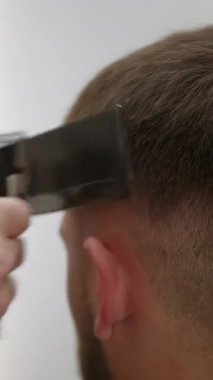 Modern bir berber dükkanında saç kesme makinesi ve tarak kullanan profesyonel bir kuaför. Kırp