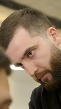 Konsantre olmuş erkek kuaför modern bir kuaförde müşterisine modern bir saç kesimi yapıyor. Kırp