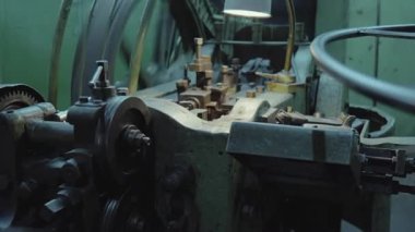 industrial engine room with large flywheel and lamp, curved belts and pulleys surrounding central crank, . Media