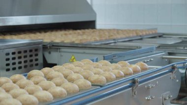 Paslanmaz kaputun altında hareket eden hamur topları taşıyan endüstriyel fırın taşıyıcısı, yakın çekim üniformalı dürbünler ilerliyor. Medya