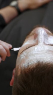 Profesyonel makyaj sanatçısı, performanstan önce beyaz temeli bir adamın yüzüne uygular. Kırp