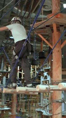 Cesur çocuk, yüksek ipli bir macera parkında asma köprüde dengede duruyor. Yaratıcı