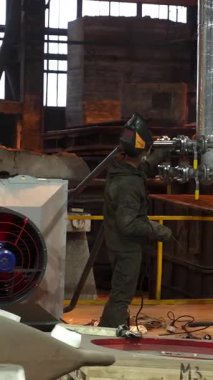 Ağır sanayi ortamında büyük bir makine çalıştıran fabrika işçisi.