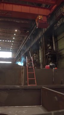 Endüstriyel işçiler büyük bir fabrikada metal parçaları üretiyorlar.