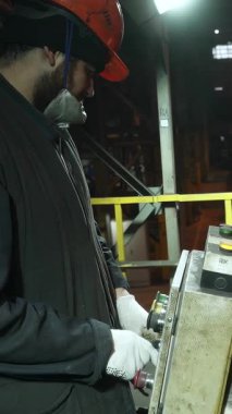 Fabrika işçisi makineleri çalıştırıyor, erimiş metali kalıba döküyor.