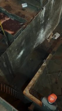 Endüstriyel işçiler fabrika ortamında büyük bir konteynıra dökülen karışımı denetliyor.