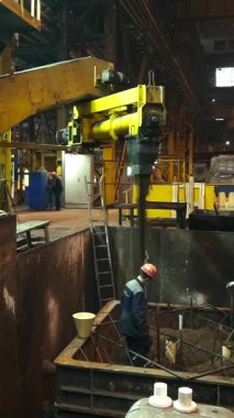 Dökümhane işçileri yoğun endüstriyel ortamda erimiş metali dikkatlice kalıba döküyorlar.