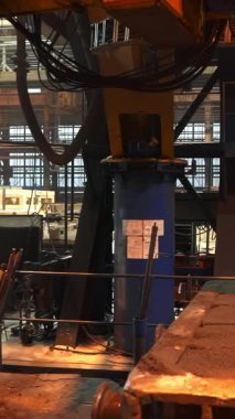 Bir fabrika ortamında metal levhaları tutan ağır makineler.