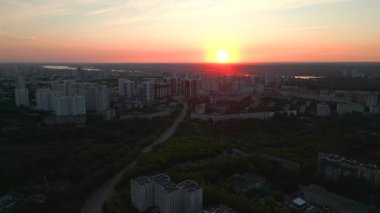 Günbatımında yüksek binaları ve yeşil parkları olan modern bir şehrin yüksek irtifa panoramik manzarası. Kırp