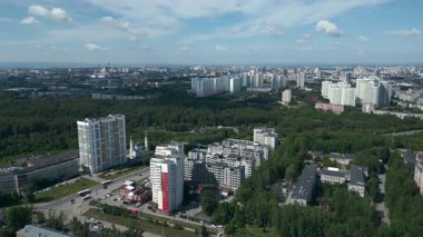 Geniş hava manzarası güneşli bir yaz gününde yeşil bir parkla çevrili modern bir yerleşim alanını gösteriyor. Kırp
