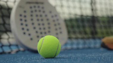 Sahada patel topu raket ve ağ yumuşak odaklı, mavi yüzey desenli, sıcak bulutlu, Medya