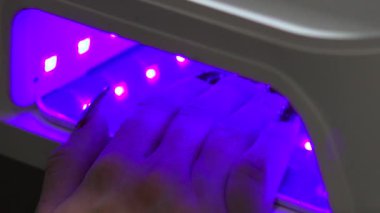 Uv lambası, mor ışığın altındaki çivileri iyileştirir, içinde el olan cihazlar, Lehçe sertleştirilmiş ampuller, salon gibi parlar. Medya