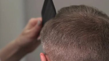 Kırpma makası soluyor ve beyaz adamı, berberi, tarağı ve elektrikli makası kullanarak temizliyor. Medya