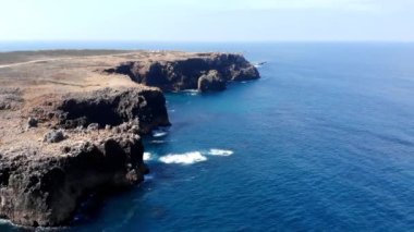 Hava Midday Rugged Cliff Coastline Manzarası Parlak Turkuaz Suyla Karanlık Kaya Yüzlerine Karşı Sörf Yapıyor. Medya