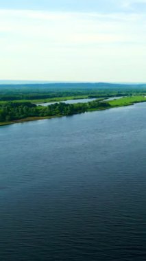 Nehir, mavi bir gökyüzünün altındaki yeşil bir arazide akar. Kırp