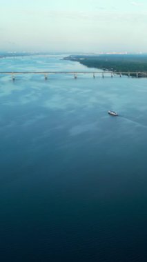 Römorkör mavnayı nehir boyunca iterek köprünün yakınına ve ormanlık nehir kıyısına getiriyor. Kırp