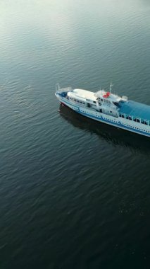 Beyaz ve mavi feribot karanlık sularda yüzüyor. Kırp