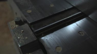 Merkezi tutkal ve cıvata delikleriyle metal masa yerleştirme, ince yansımalar, talaş parçacıkları ve aşınmış atölye. Medya