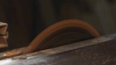 Dairesel testere, hareket bulanıklığı ile sert kereste kesiyor, dönen bıçağı ve uçan çipleri yakın açıyla yakalıyor. Medya