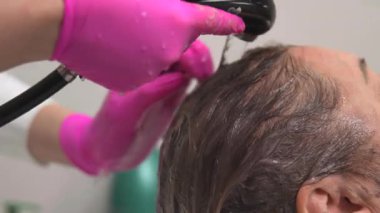 Kafkasyalı müşteri son durulama ve kafa derisi masajı alıyor stilist sabit su akıntısı ve parmak ucu kullanıyor. Medya