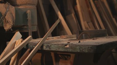 Dusty Bench 'teki zımpara makinesinin yanına yığılmış odun şeritleri, çeşitli kesikler ve eğimli paneller. Medya