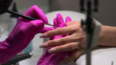 Cilalı ve pürüzsüz kenarlar yaratmak için manikürdeki son rötuşları fırça darbeleriyle ve nazikçe cilalamak. Medya.