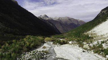Uçsuz bucaksız bir dağ vadisinde dolambaçlı bir nehri ve yemyeşil ormanları olan çarpıcı hava görüntüleri. Medya