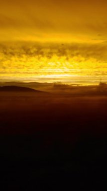 Bulutların arasından nefes kesen altın gün doğumu yavaş yavaş engin, karanlık ve sisli bir manzarayı ortaya çıkarıyor. Medya