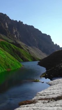 Hava turkuvaz alp gölü karları erir ve kristal sahil sükunet havzası dik yeşil yamaçları yansıtır. Medya