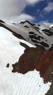 Koyu kayalıkların etrafında eriyen kar tarlası. Tırmanışçı tırmanışı için karlı bir yol. Medya