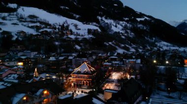 Alpine Tatil Gecesi Aydınlatılmış Meydanı, Şenlikli Işıklar ve Ağaçlarla süslenmiş, Karla Kaplanmış. Medya