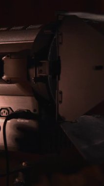 Film ekibi karanlık bir stüdyoda güçlü bir fresnel lens ışığını açıp kapatıyor. Medya