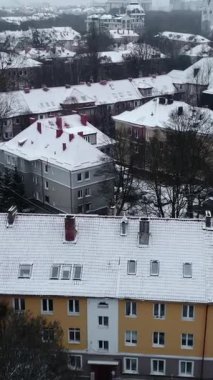 Soğuk bir kış günü karla kaplı çatıları olan bir Avrupa şehrinin üzerinde uçan insansız hava aracı. Medya