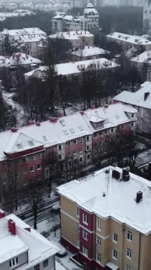 İnsansız hava aracı şehir binaları ve caddelerin üzerinde uçuyor. Taze kış karlarıyla kaplı. Medya