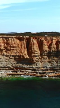 Zümrüt suyun üzerindeki kireçtaşı uçurumlar korunaklı koyda, katmanlı kaya raflarında, çakıl taşlı çıkıntılarda,