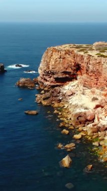 Açık deniz kaya adaları, derin mavi okyanus, hafif dalgalar, seyrek kıyı bitkileri ile hava dingin uçurum,