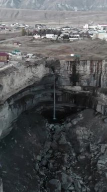 Hava manzaralı, gün ışığında köy yakınlarında devasa bir obruk. Dik kireçtaşı duvarlar ve çökmüş krater tabanı.,